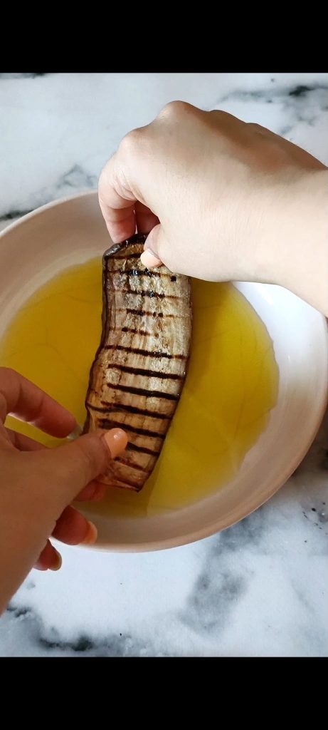 Doop elke plak gegrilde aubergine in olijfolie
