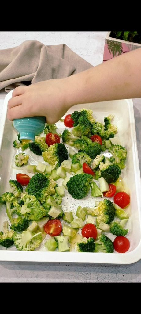 Tomaatjes en broccoli in een ovenschaal en kruiden met olie, oregano, zout en peper
