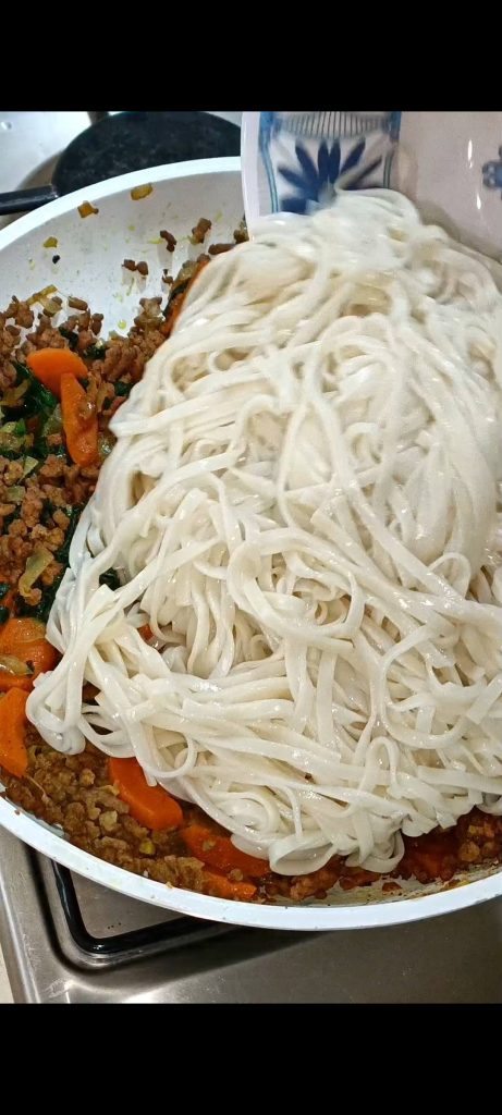 We koken de noedels en voegen ze toe aan de pan met de saus