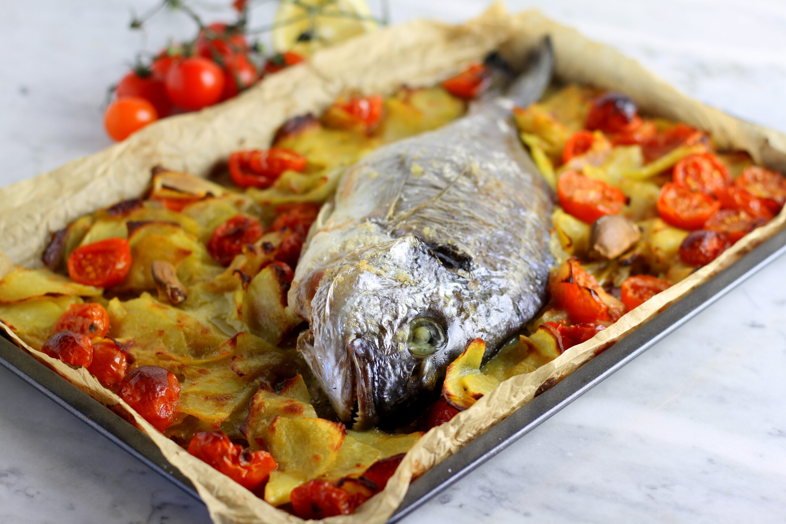 Dorade uit de oven met aardappelen, kerstomaten en knoflook