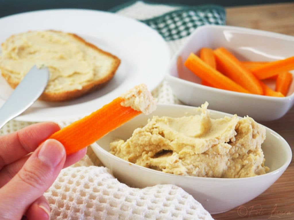 kikkererwtenhummus in een kom met sneetjes brood en wortels