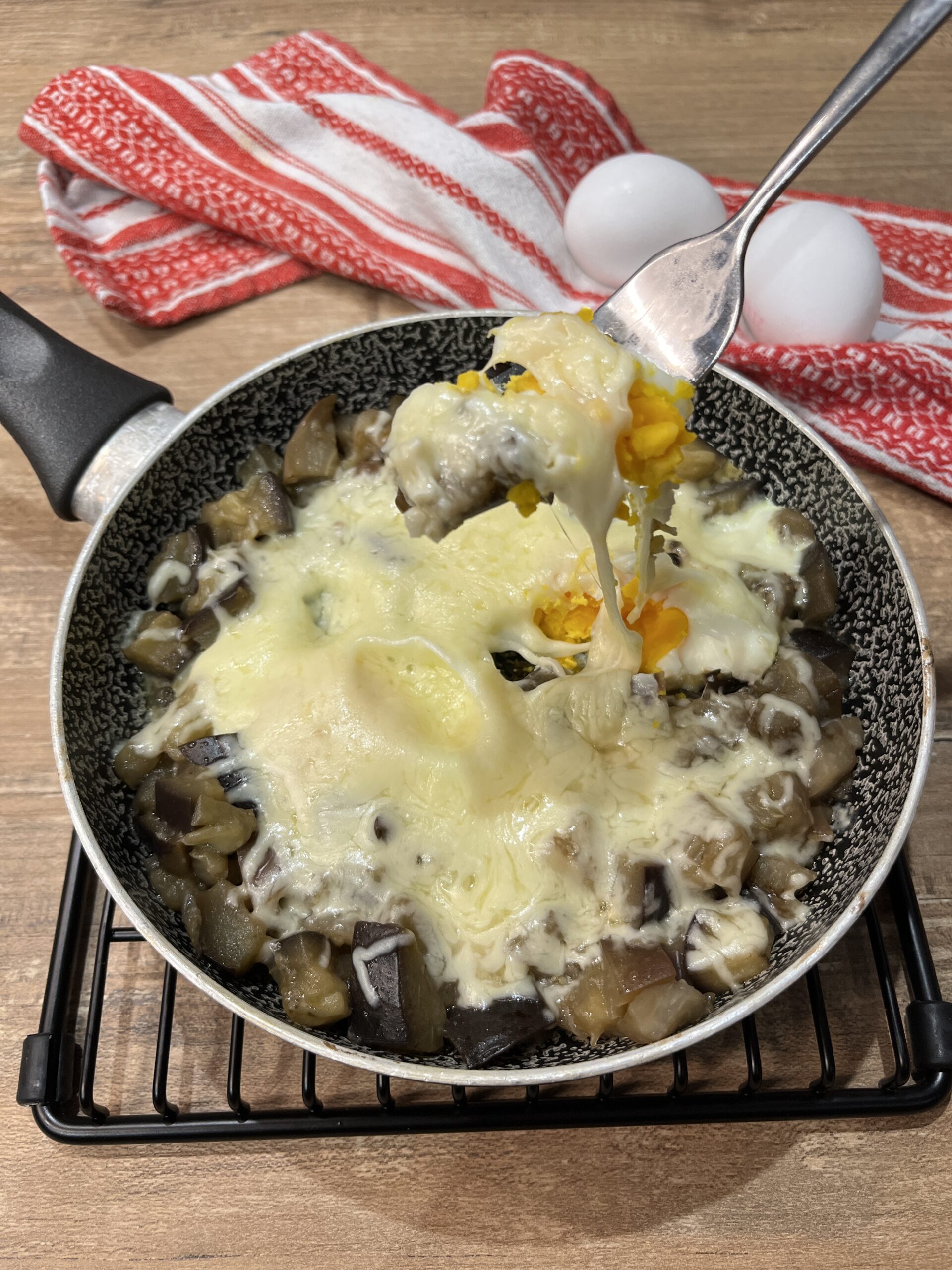 Gesmolten eieren in de pan met aubergines