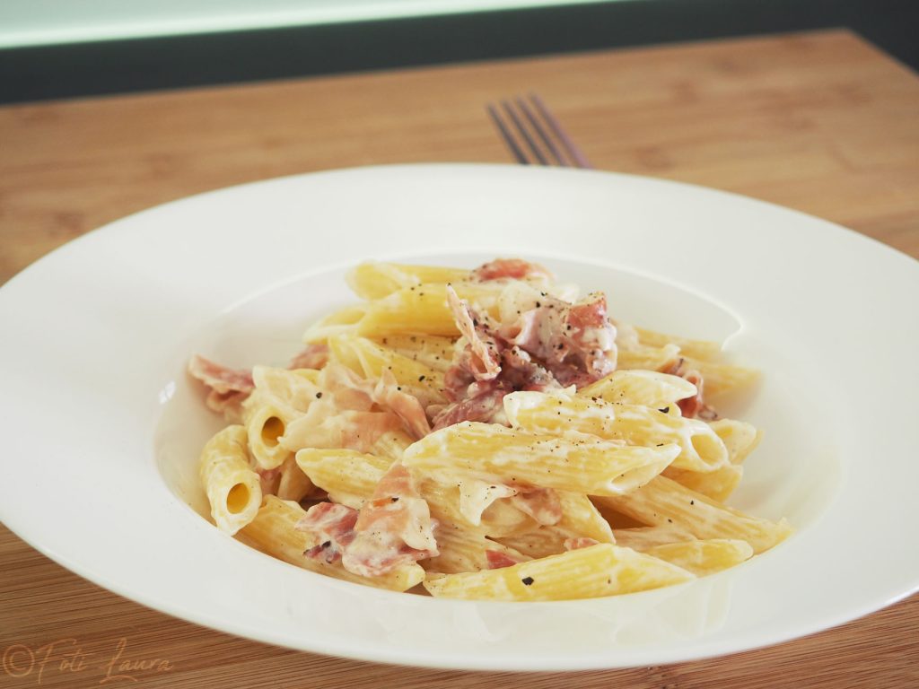 bord met pasta, room, ui en spek