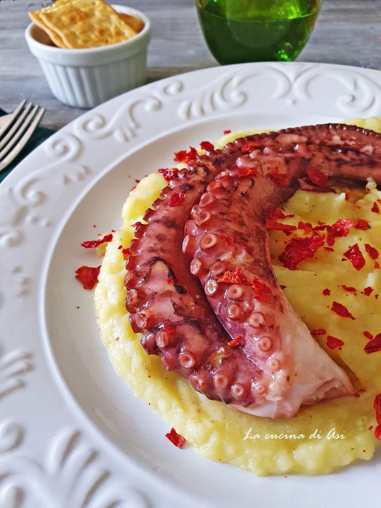 Krokante octopus geserveerd op aardappelpuree en verkruimelde cruschi paprika's – een elegant en eenvoudig hoofdgerecht, perfect voor de feesttafel.