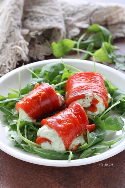 verdeel wat rucola over een bord en leg de koude paprikarolletjes erop