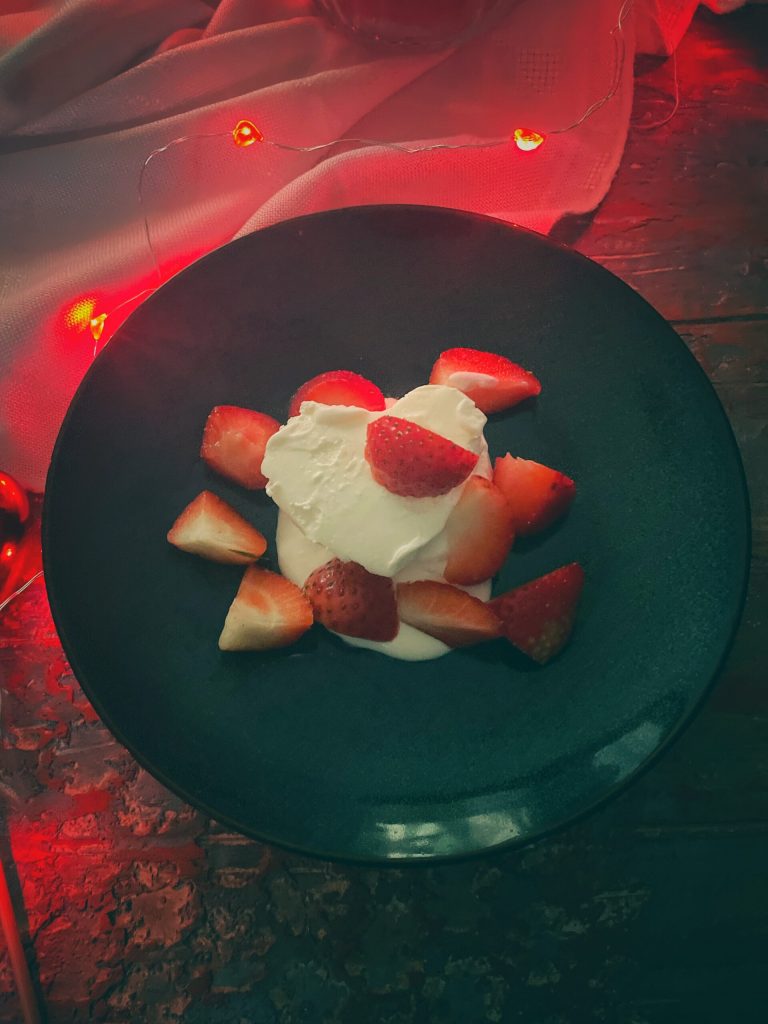 Detail van Coeur à la crème met aardbeien op een zwarte achtergrond.