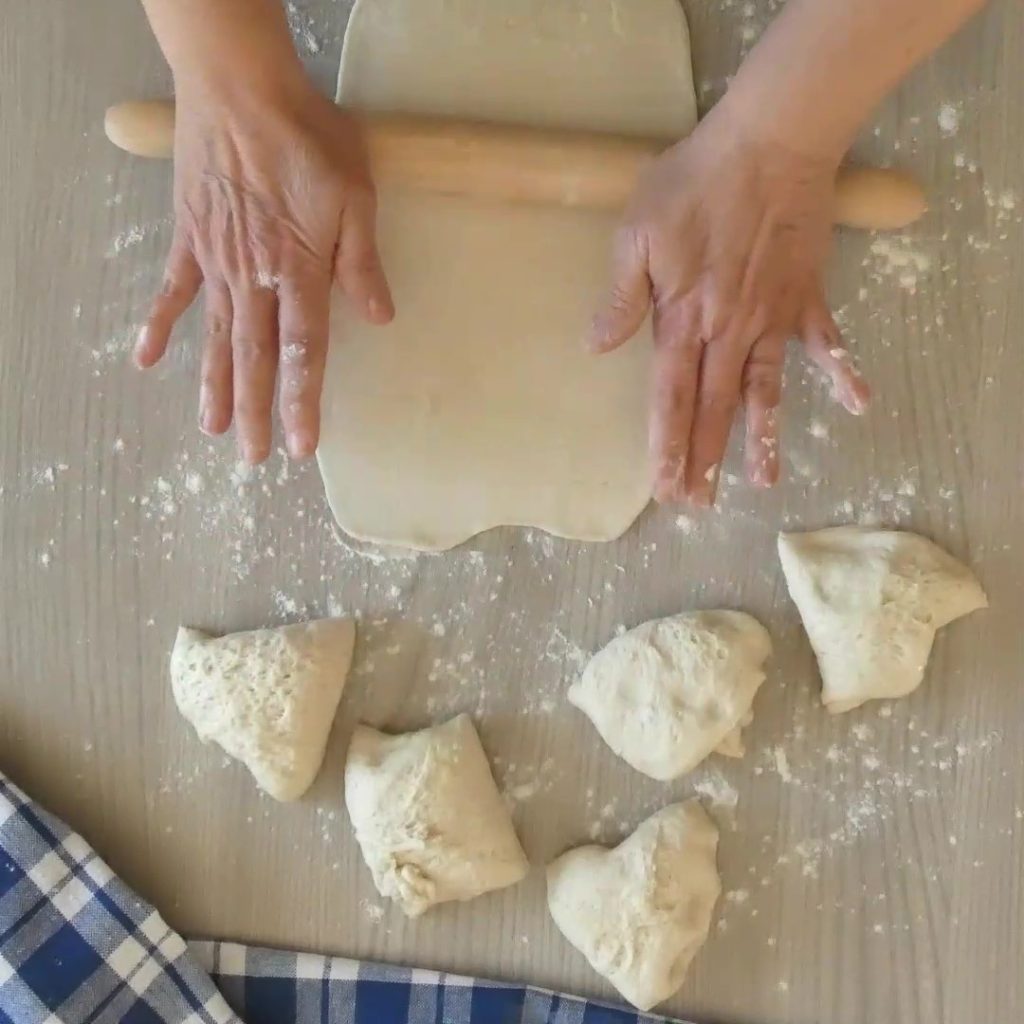 focaccia in de pan met worst en olijven uitrollen deeg
