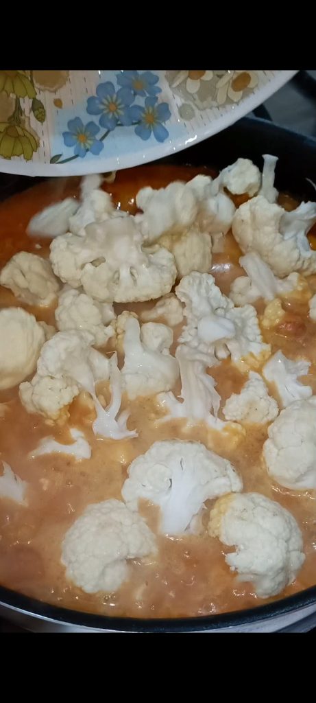 Voeg tomaat, kokosmelk, groentebouillon en bloemkool toe