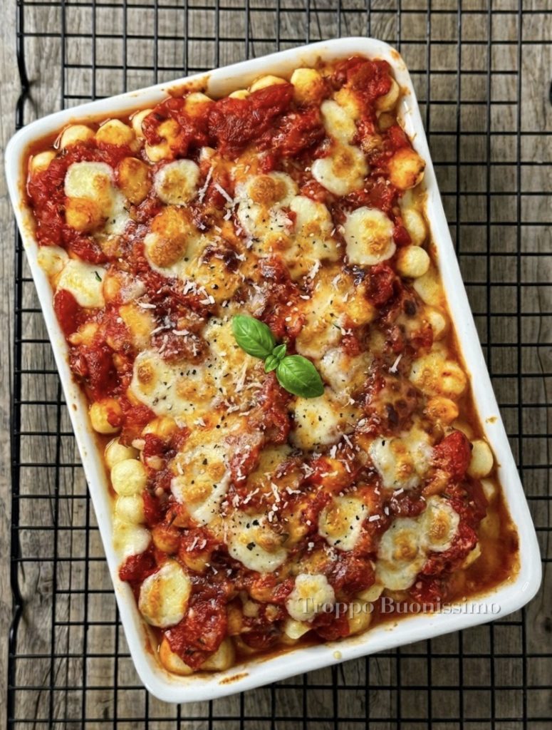 Ovenschaal met gnocchi alla Sorrentina net uit de oven, met veel gesmolten mozzarella en een goudbruine korst