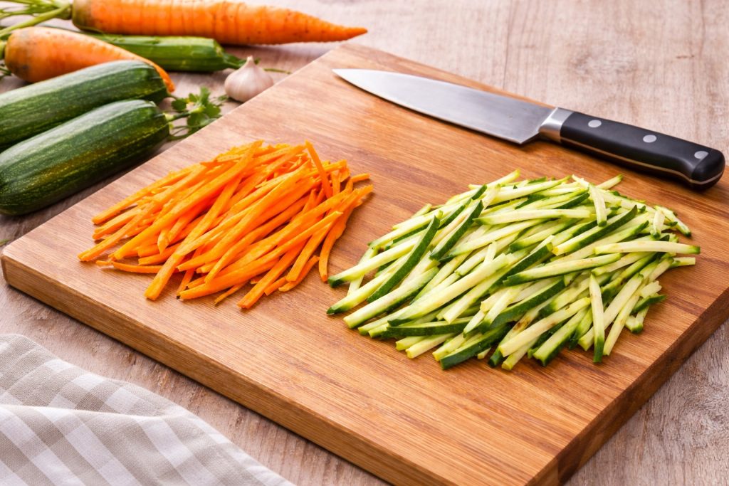 julienne van courgette en wortel op een houten snijplank