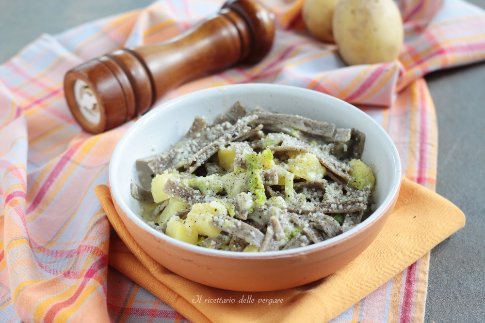 Schaal met pizzoccheri uit de Valtellina met savooiekool, aardappelen en gesmolten fontina, geserveerd in een keramische ovenschaal.